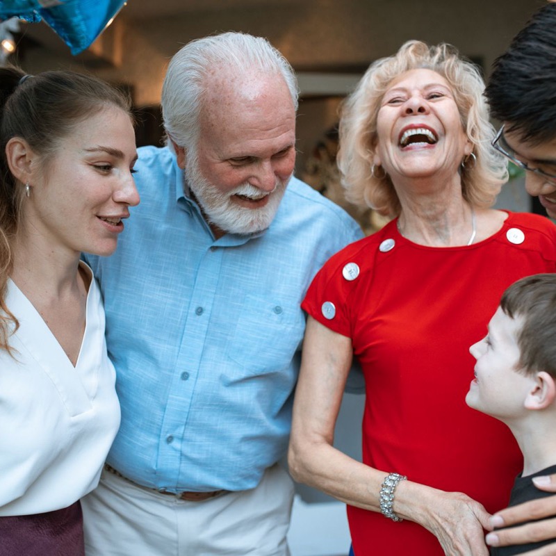 Grandparents laughing with their children and grandchild at a family celebration