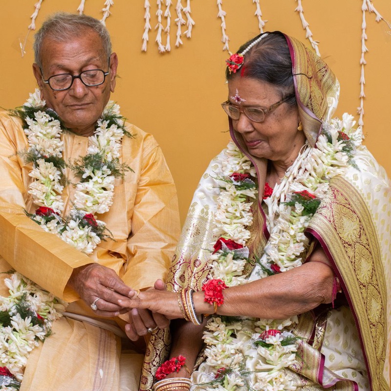 An elderly couple at their celebration, garlanded with tuberose flowers